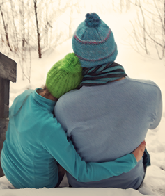 Two people hug in a winter landscape.