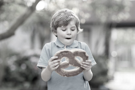 Little boy holding huge sweet pastry.