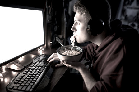 Teenager playing computer games and eating.
