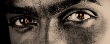 Small flames reflected in a man’s eyes illustrates his determination. 