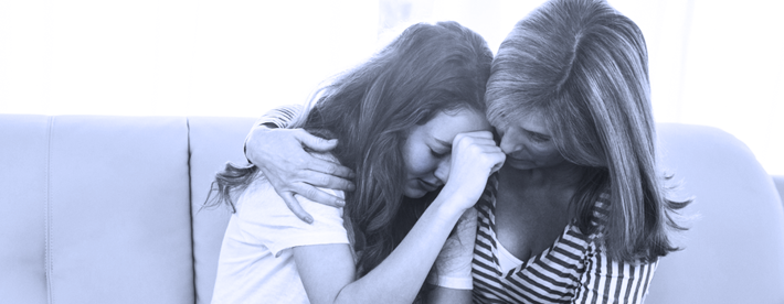 Mother concerned about and comforting troubled teen daughter. 