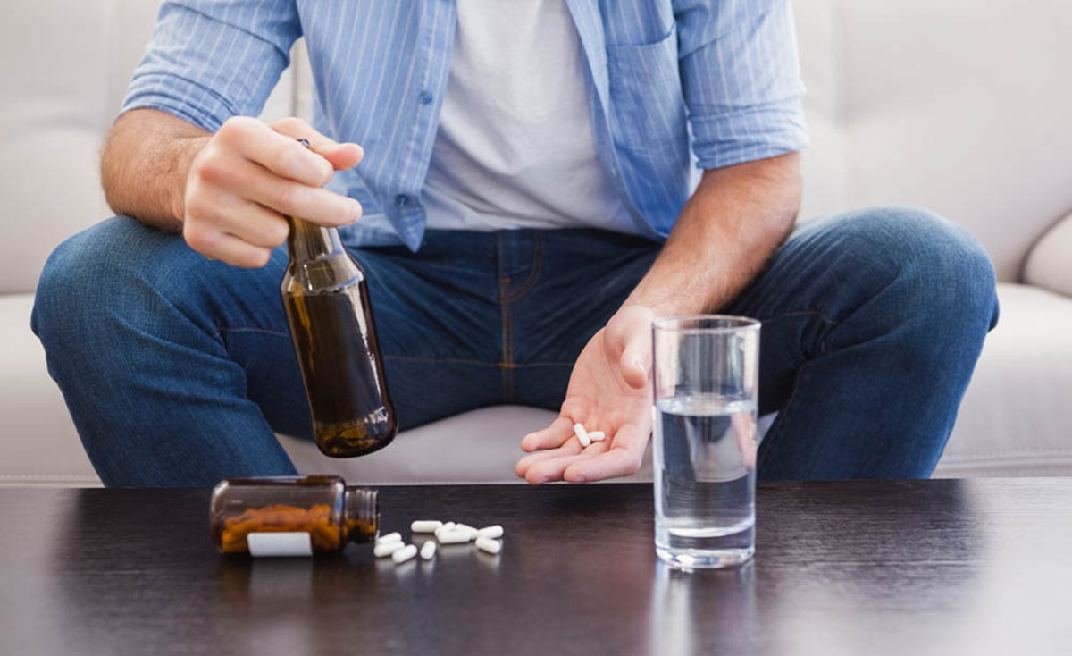 guy taking alcohol and pills