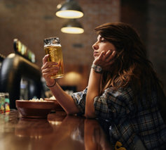 Sad young woman is looking at a beer glass