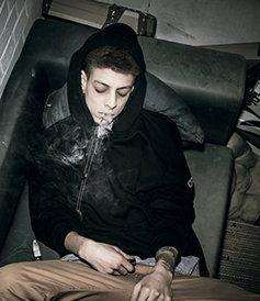 Addict young guy smocking on the couch