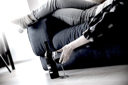 Person drinking wine at home, laying on the couch 