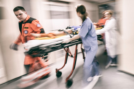 Paramedics and nurse pulling hospital trolley