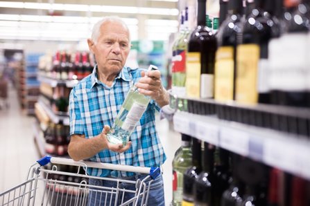 An old man is buying alcohol in a supermarket