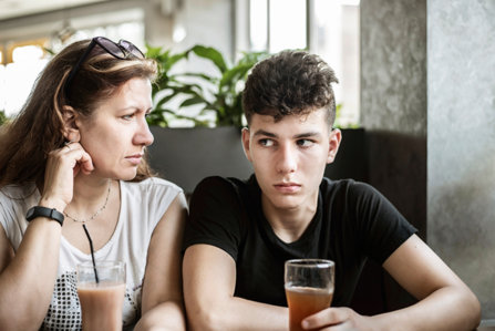Mother and son in a cafe. Son looks suspicious.