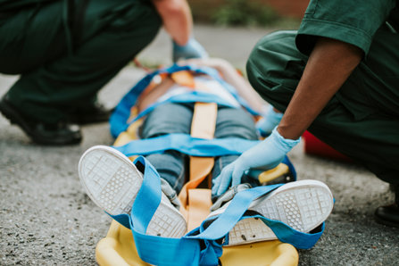 Paramedics strapping a teenager to the stretchers.