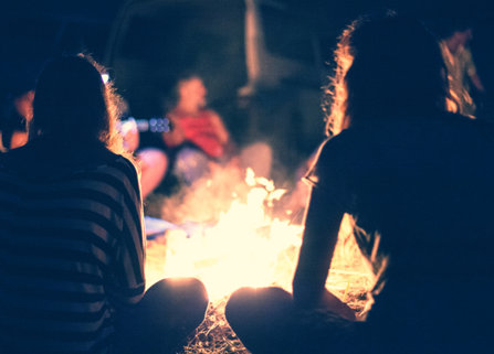 Teenagers sit by a fire