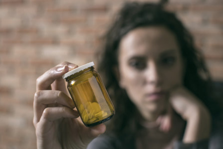Young woman holding and looking on a pill.