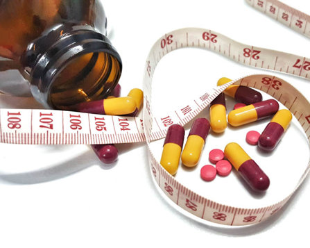 pills and a tape measure used to check weight loss