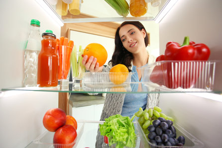 Woman takes fruits from the fridge