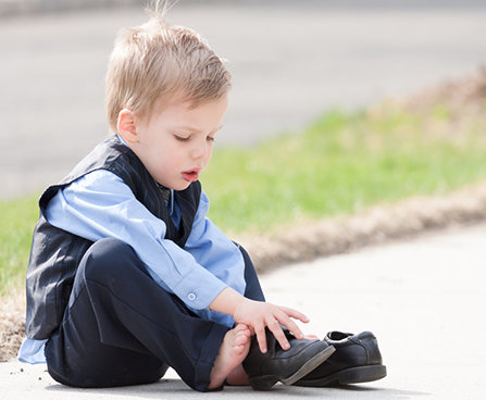 A young child tries to put on his shoes. 