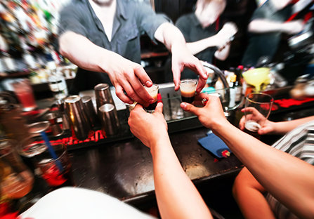 A bartender hands out more drinks. 