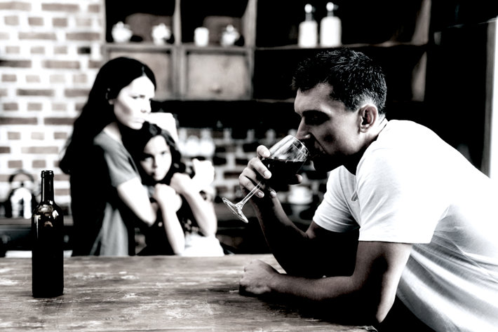 Husband drinking in front of his family.
