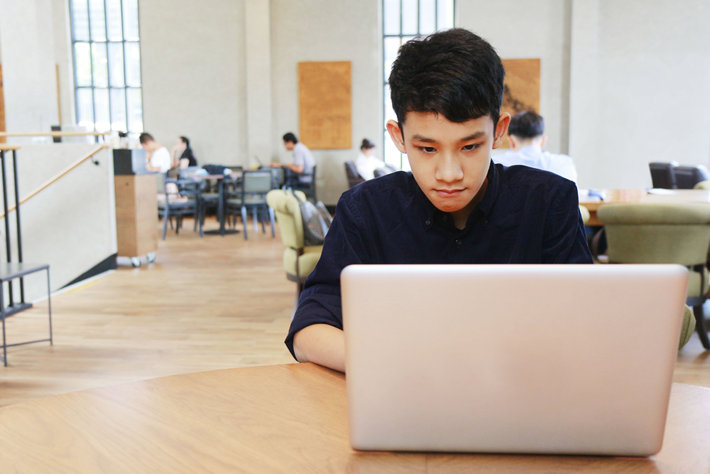 Asian boy studies at a laptop. 