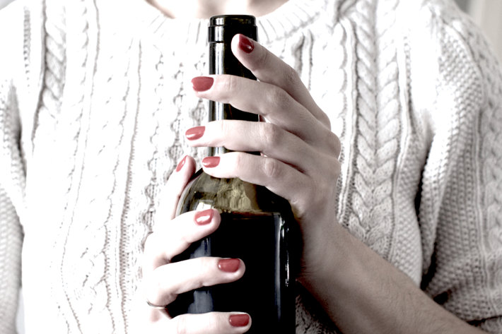 Woman holding bottle of wine.