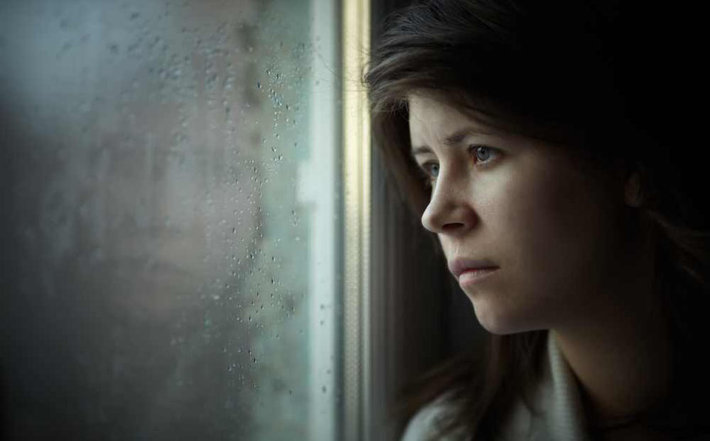 woman staring lifelessly out window