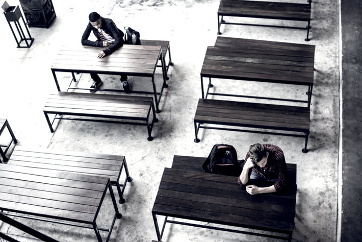 Teenage boys sitting in an empty college dinning room