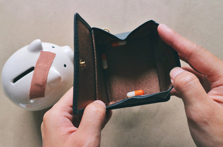 An open and empty wallet with few pills inside.
