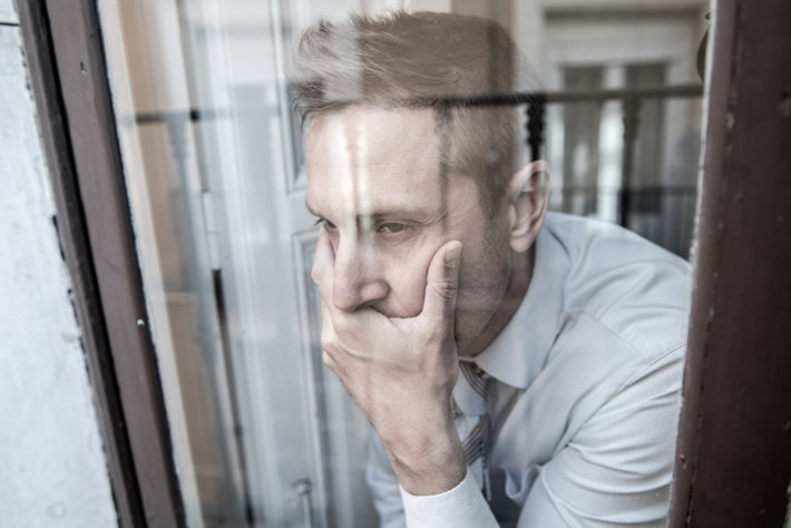 Depressed man looking at the window.