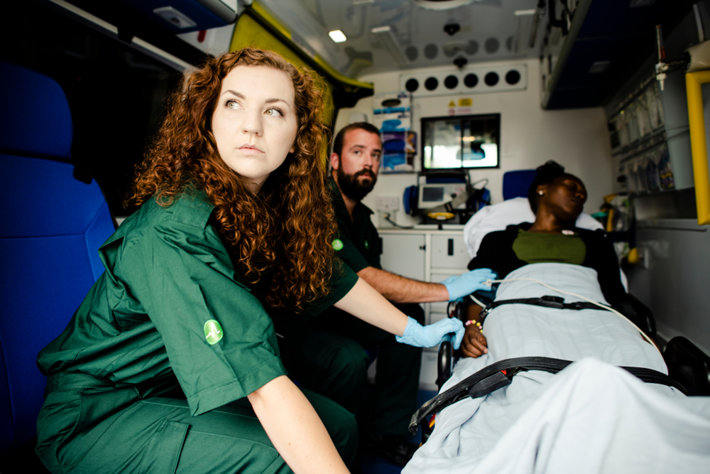 Paramedics inside ambulance car with a patient.
