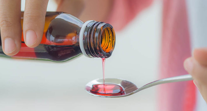 cough syrup being poured into a spoon