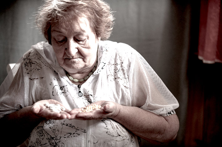 Sad old woman holding drugs.