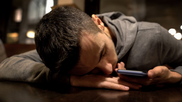Man asleep, holding a smartphone.