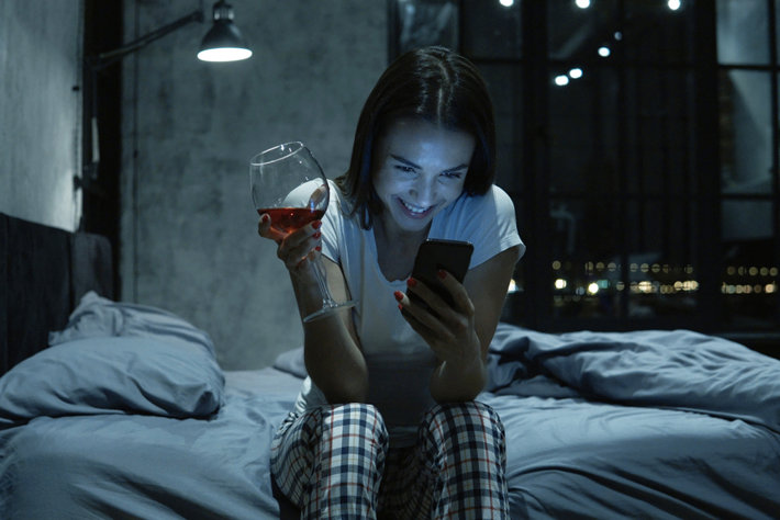 Woman alcoholic looking in her phone at night.