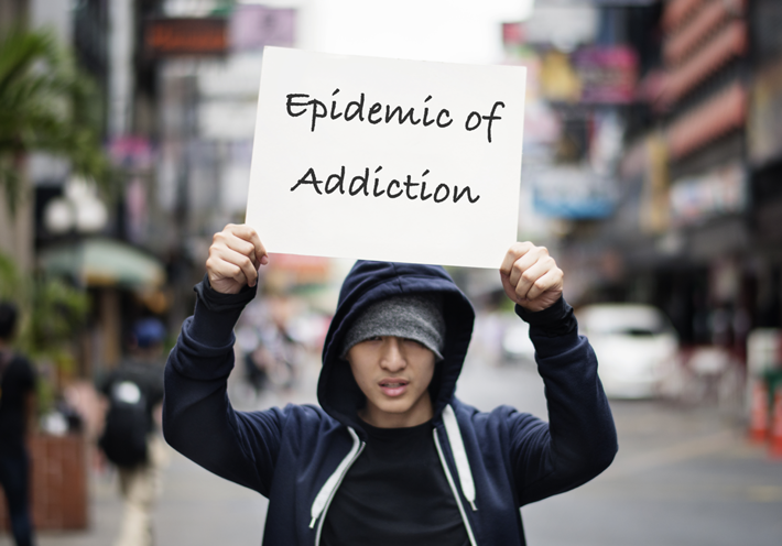 Young guy holding sign - Epidemic of Addiction