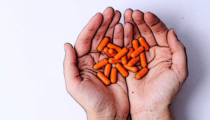 Orange pills in hands.
